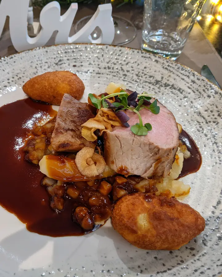 Angerichteter Teller mit Kalbfleisch, Jus, Pastinaken und Kartoffelkrapfen
