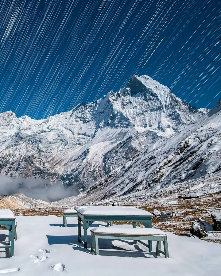 Verschneite Berge unter einem Sternenhimmel mit Sternspuren