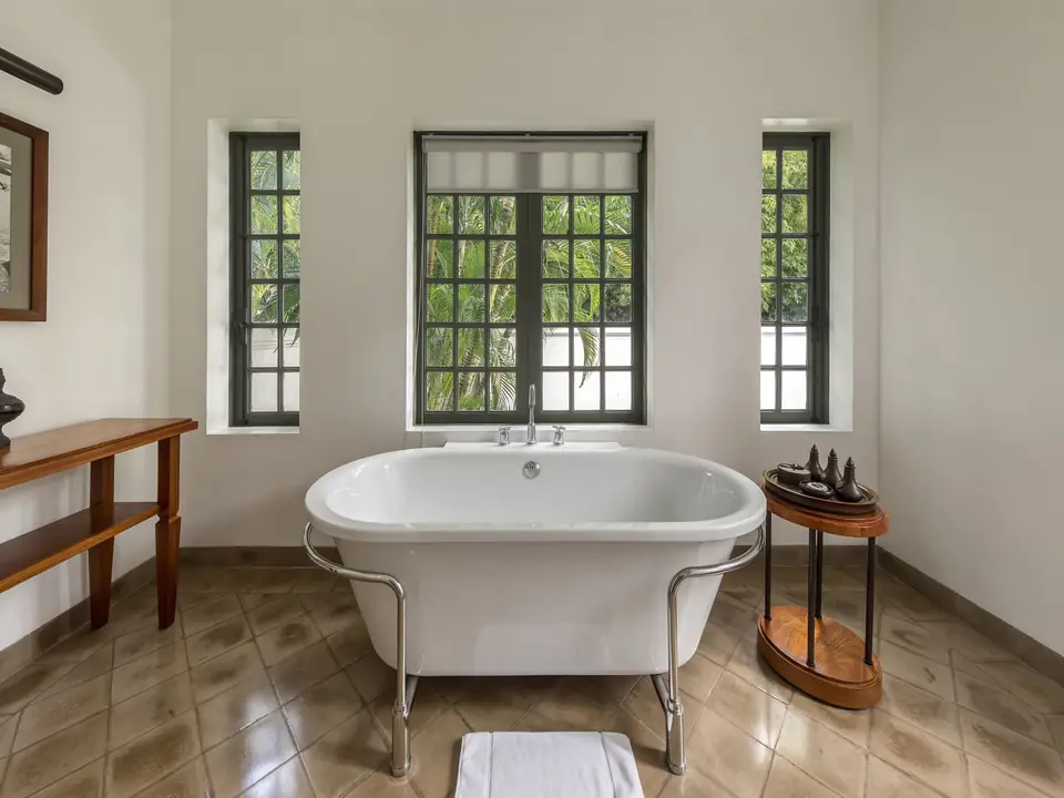 Freistehende Badewanne in einem hellen Raum mit hohen Fenstern