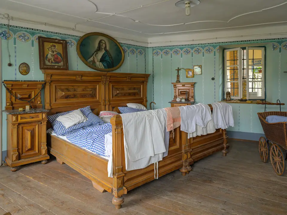 Gästezimmer mit bemaltem Holzbett, grünen Wänden und Sprossenfenster